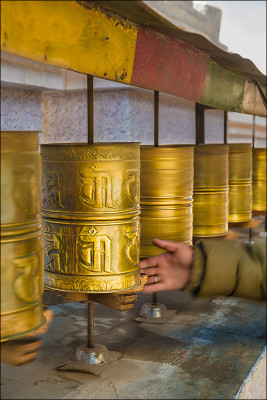 The hand of a Ladakh resident spins the long row of prayer wheels as he passes by.