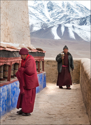 A Buddhist monk and a pilgram pause at the prayer wheels while making their ascent to the monastery.